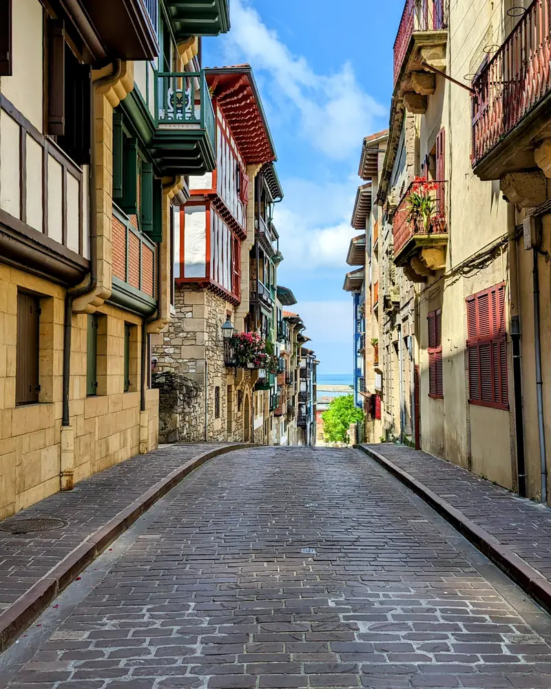 Una calle empedrada entre casas de colores con balcones de madera, en Hondarribia.