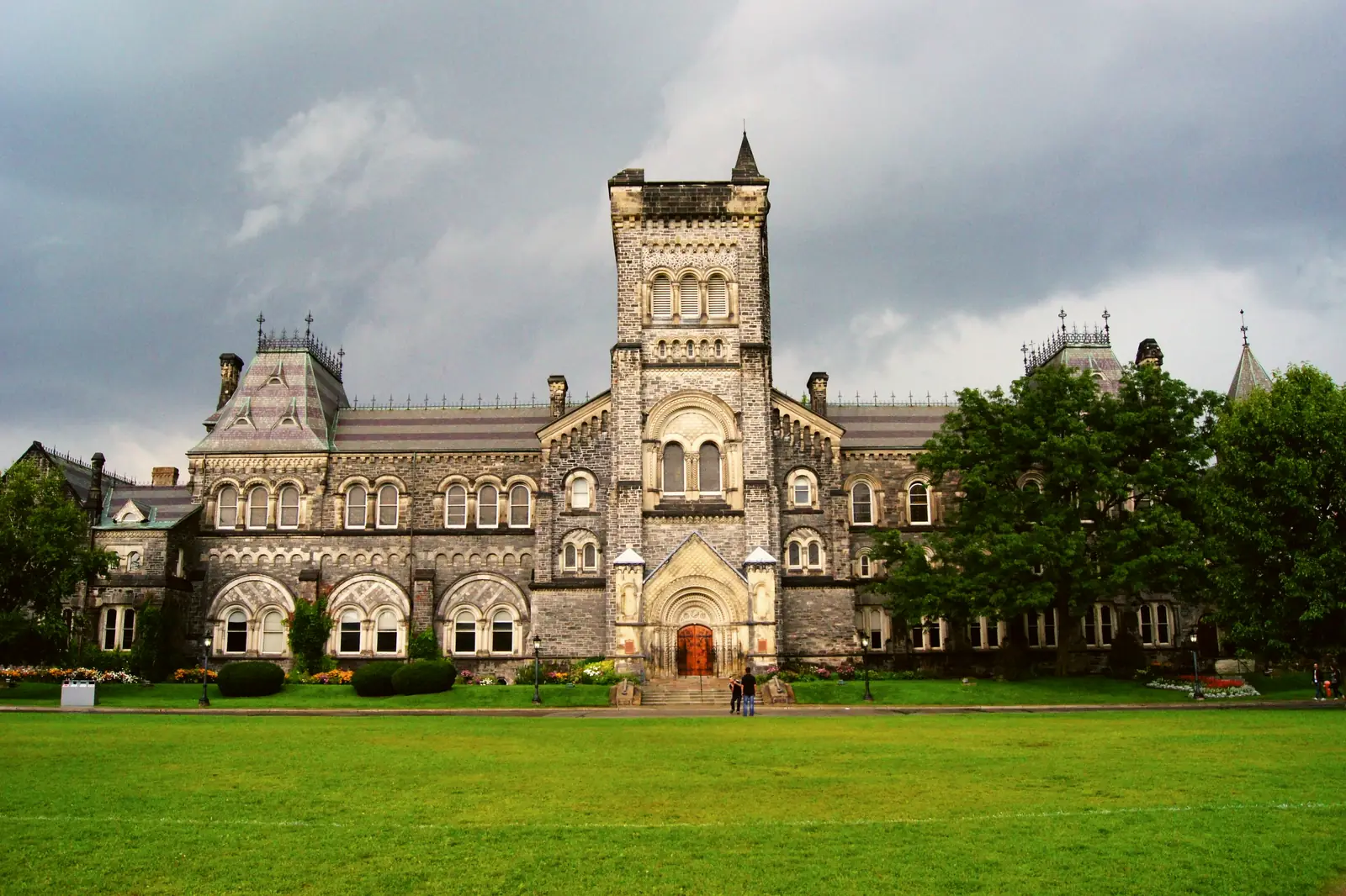 Edificio histórico de piedra con una torre en un campus universitario de Canadá.