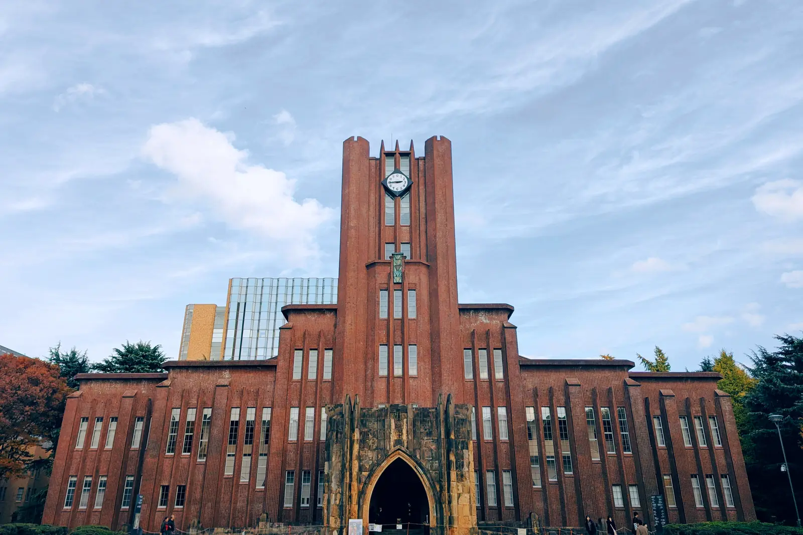 Edificio de ladrillo con una torre en un campus universitario de Japón.
